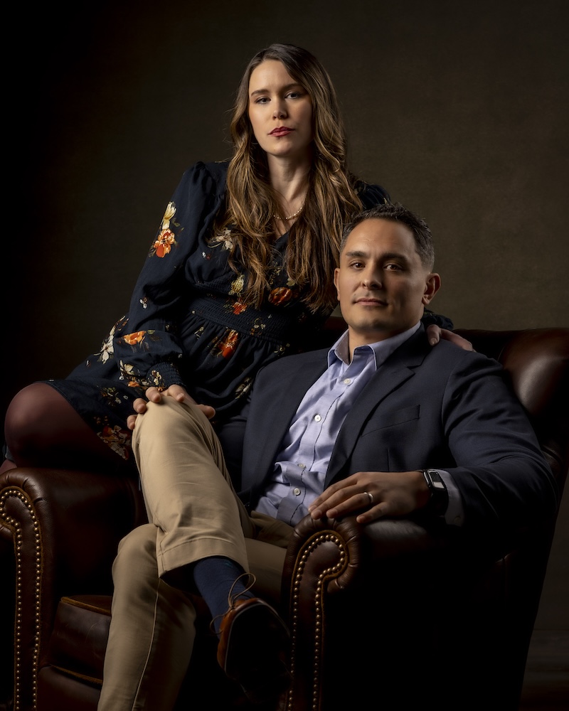 West Hartford Headshot Photographer creates a cinematic, fine-art portrait of a stylish couple posed in a leather armchair, featuring dramatic lighting and refined wardrobe styling.