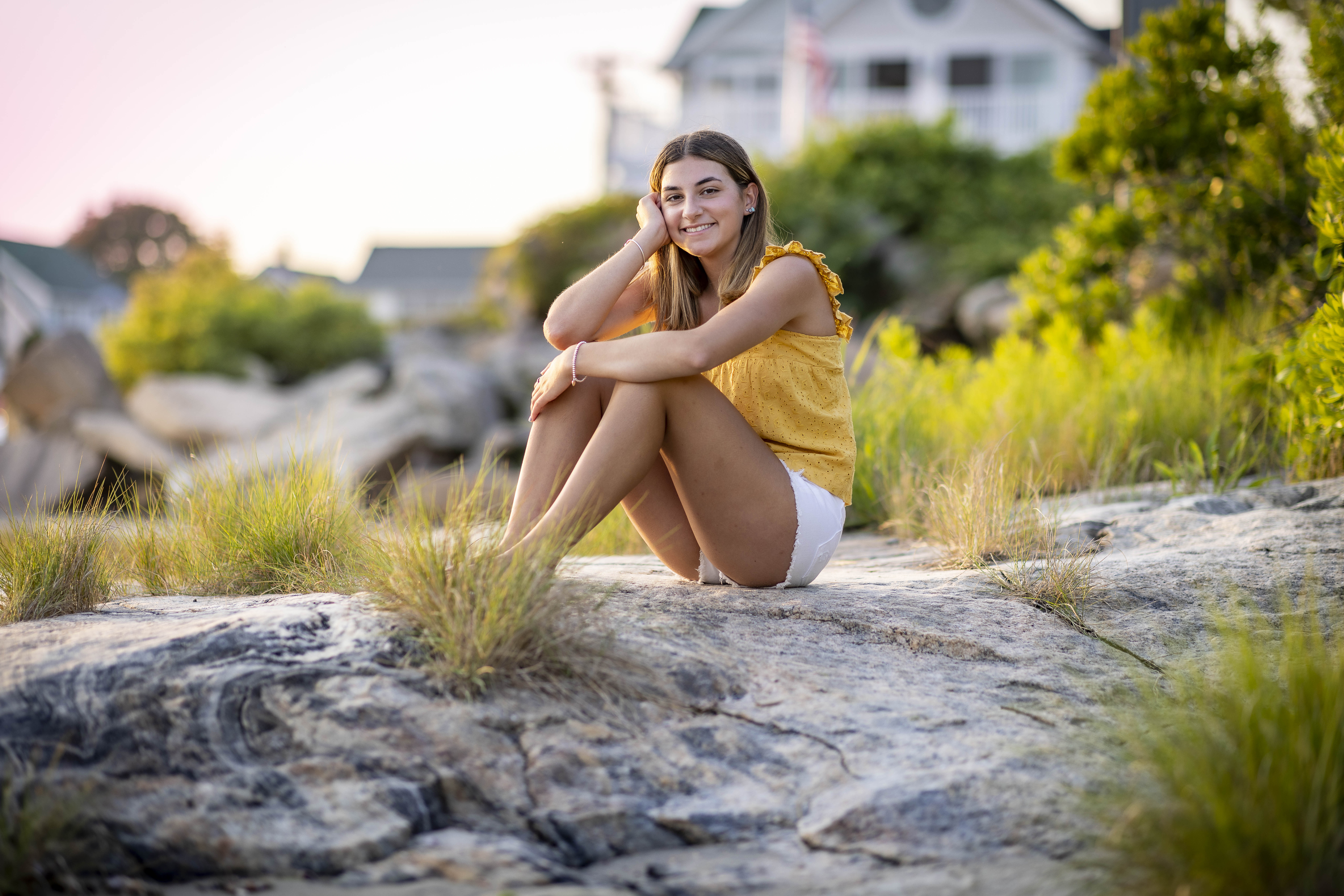 Rob Faber Photography | Senior Portraits | Senior Photos | High school senior seated on sunlit coastal rocks during an outdoor senior portrait session, showcasing relaxed posing and natural light in Connecticut.