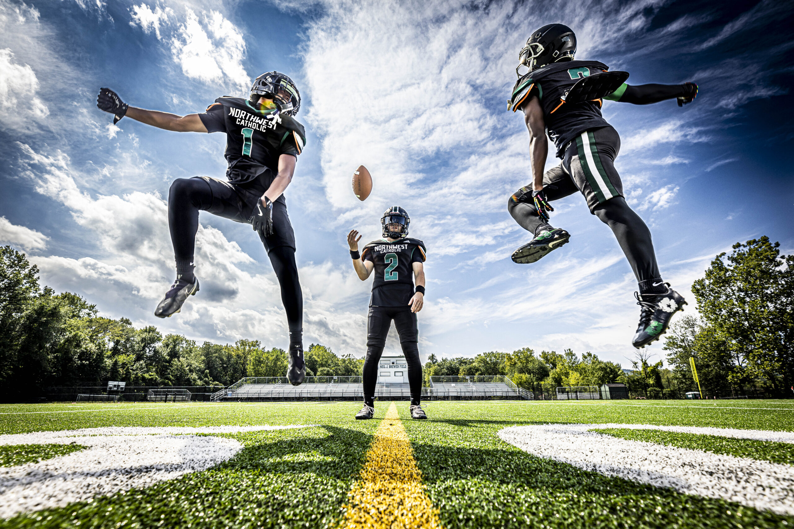 CT Sports Photographer media day portrait of three high school football players in uniform on the field, action shot with dramatic sky.