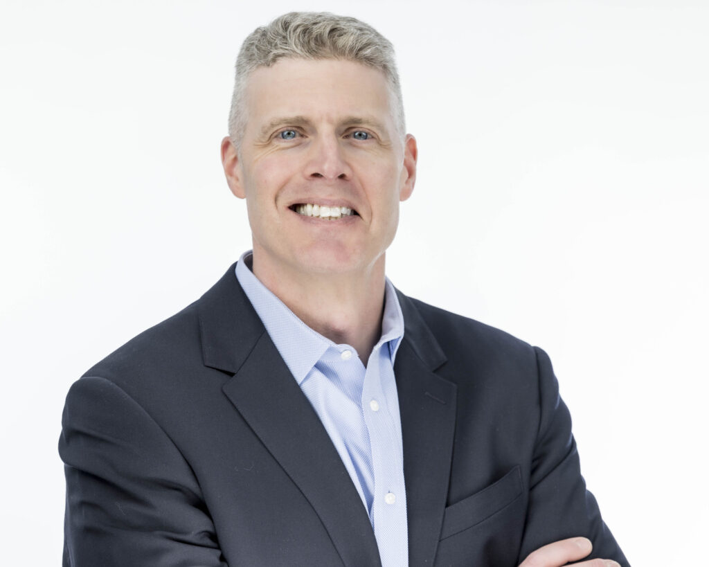 Professional headshots in CT of a confident male business professional wearing a dark suit jacket and light blue shirt, photographed against a clean white background with arms crossed to convey leadership, trust, and professionalism.