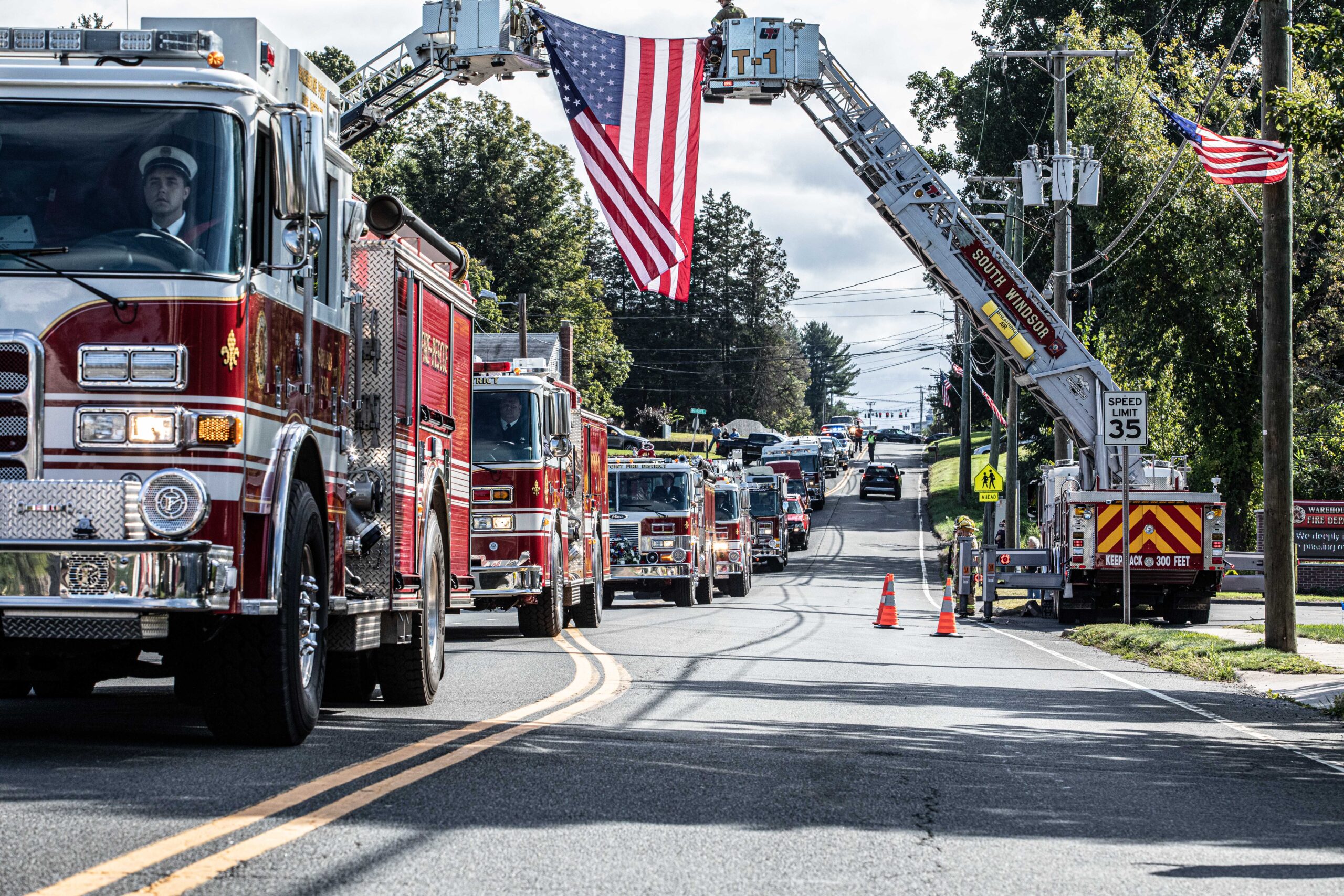Photographer in CT | CT Photographer | Suffield Photographer captures a line of fire trucks under a large American flag displayed from ladder trucks during a community event.