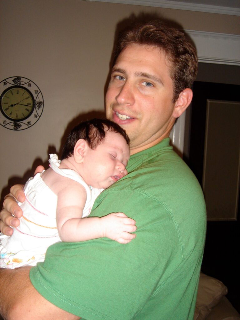 Photographer in CT | CT Photographer | Suffield Photographer | father holding his newborn baby at home, capturing the intimacy of early parenthood.