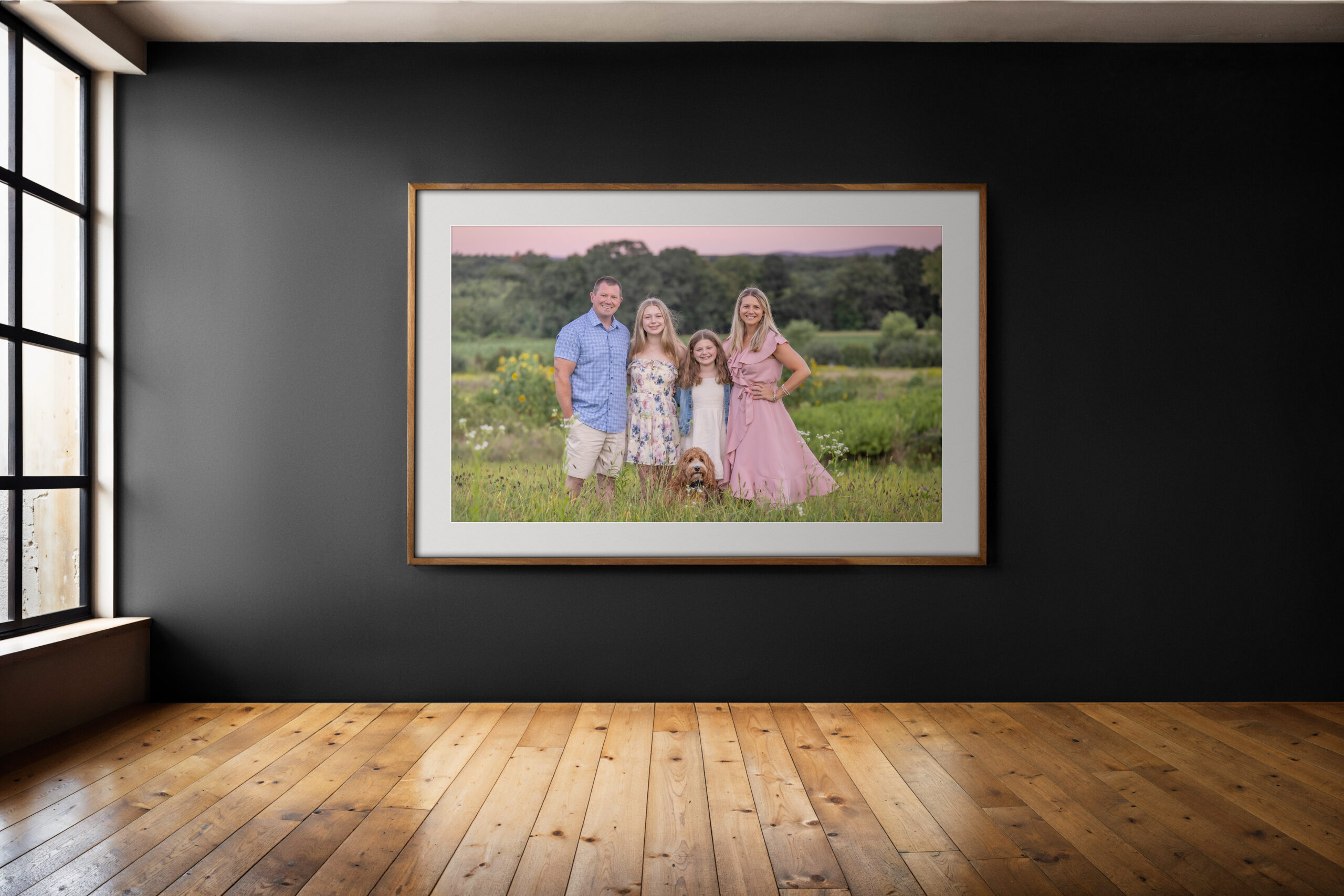 CT Family Photographer wall art display of a framed family portrait in a modern home, featuring parents, children, and scenic outdoor background.