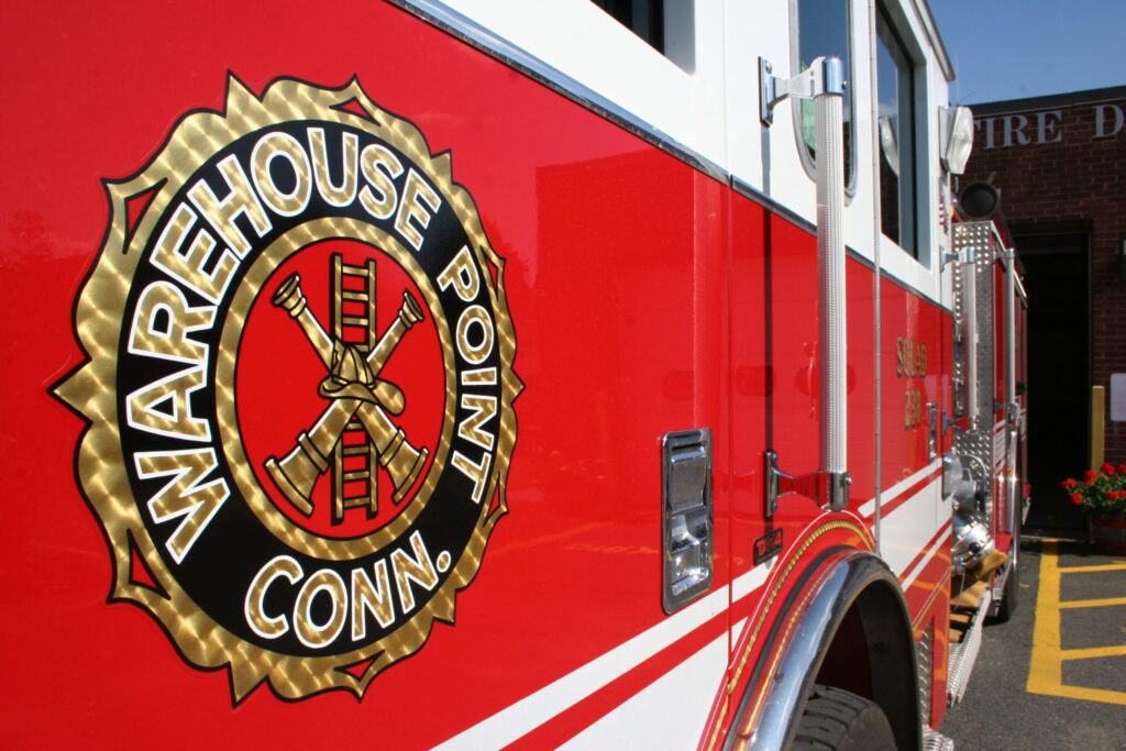 Photographer in CT | CT Photographer | Suffield Photographer highlights the Warehouse Point Fire Department emblem on a bright red fire truck during daylight.