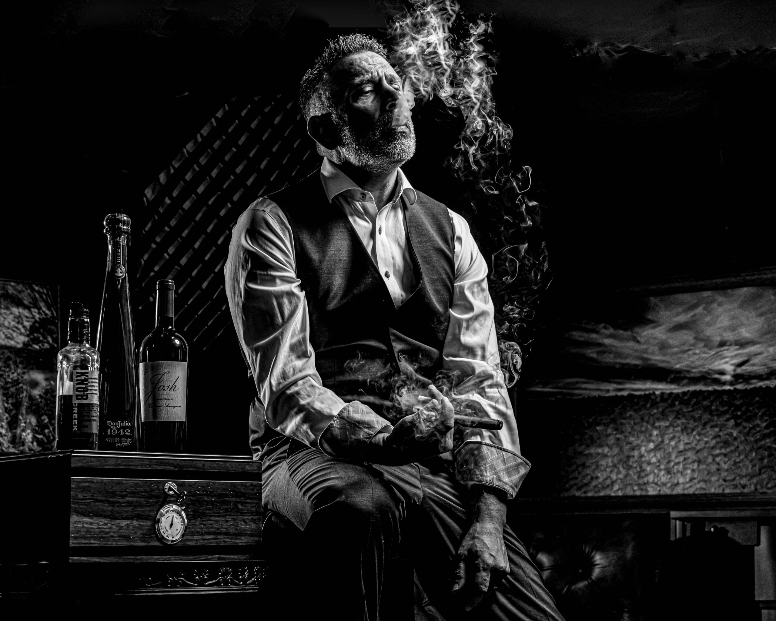 Rob Faber Photography | Business Branding Photography | Branding CT | Cinematic black and white branding portrait of a man in a vest and tie smoking a cigar, styled with dramatic lighting and vintage props to convey confidence, authority, and bold brand identity.