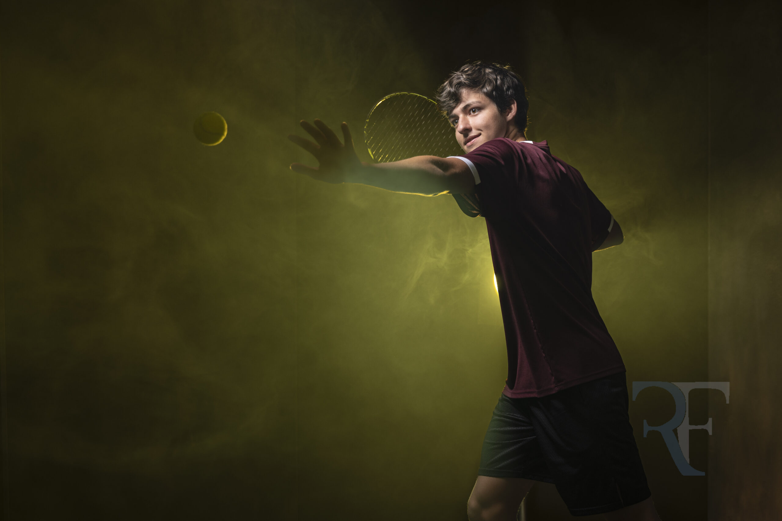 Photographer in Simsbury | Rob Faber Photography | Cinematic senior portrait of Thomas in a maroon shirt playing tennis, captured with dramatic studio lighting and smoke effects for a bold fine-art look.