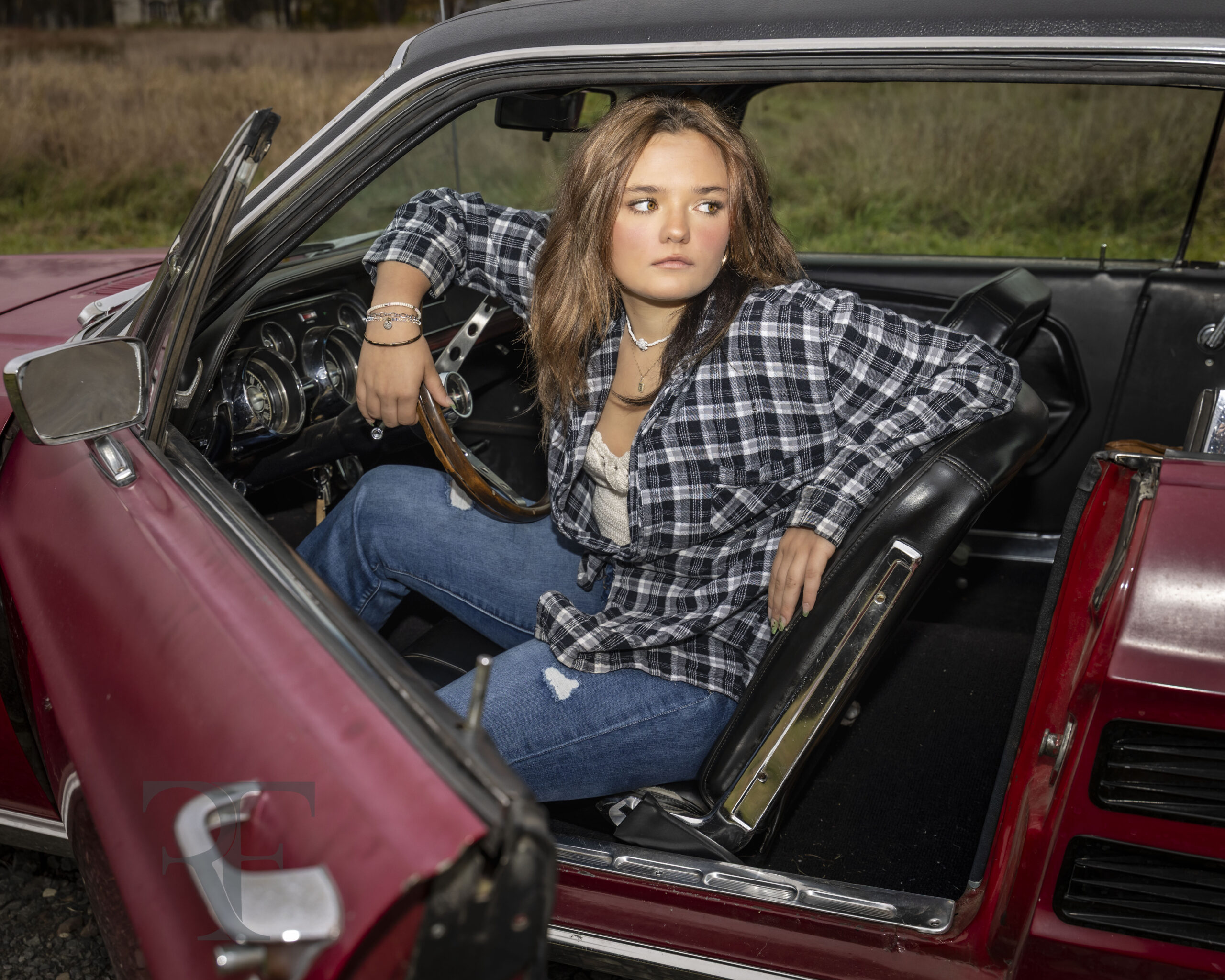 Cinematic senior portrait of Emma in driver’s seat of red 1967 Ford Mustang beneath dramatic sky in Suffield CT; fine-art photo by Rob Faber Photography.