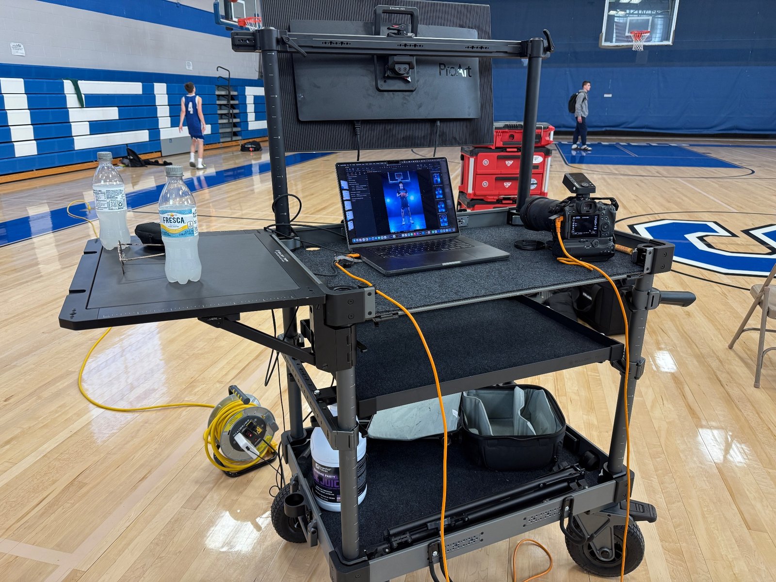 Professional tethered photography workstation used during a CT basketball media day, featuring a camera connected to a laptop for real-time image review and sports portrait workflow in a high school gym.