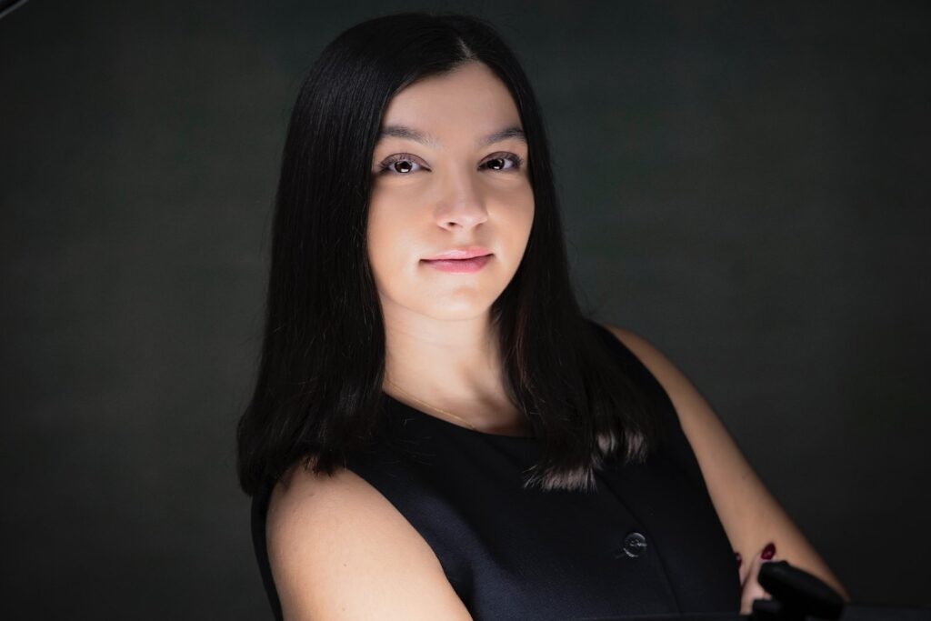 Rob Faber Photography | Headshot Photos | Professional headshot of a young woman with dark hair wearing a black sleeveless top, photographed in studio lighting against a dark background to convey confidence and professionalism.