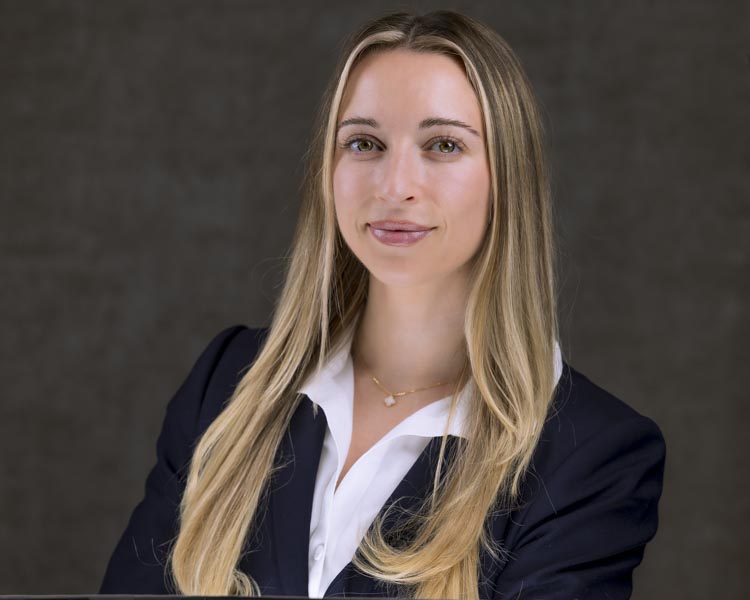 Rob Faber Photography | CT Photographer | Professional Headshots | Professional corporate headshot portrait of a young woman with long blonde hair wearing a navy blazer and white blouse against a dark studio backdrop, photographed with clean professional lighting for branding and business profile use.