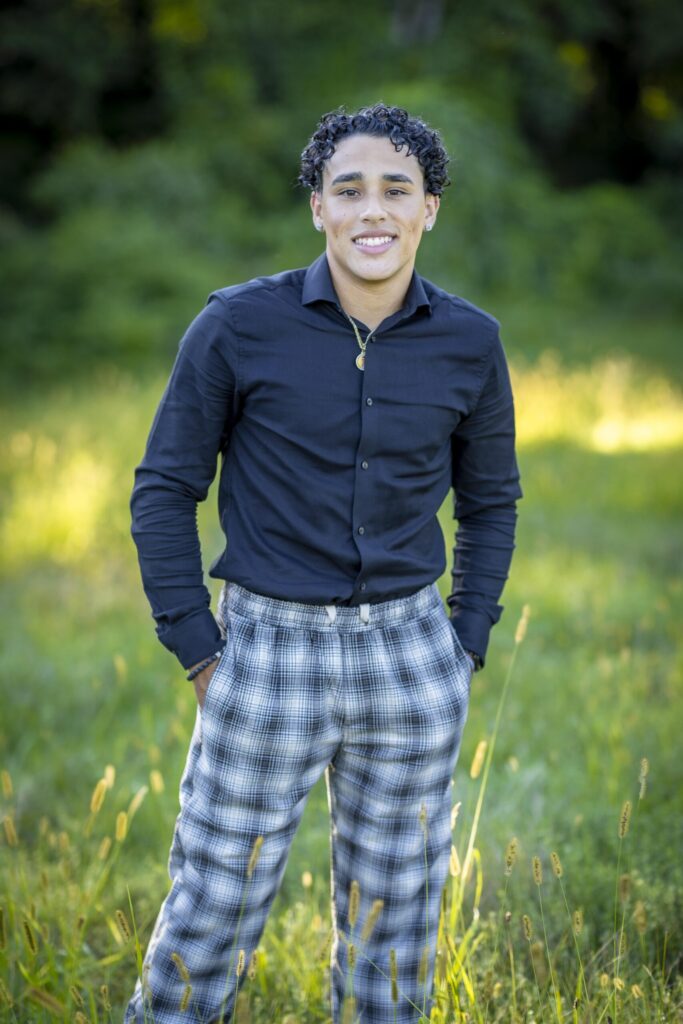 Rob Faber Photography | FBR Media | Senior Guys Portraits | Senior portrait of a smiling high school guy standing outdoors in a grassy field with cinematic natural light