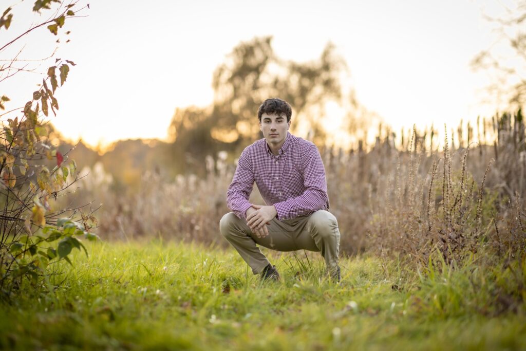 Rob Faber Photography | FBR Media | Senior Guys Portraits | Outdoor senior portrait featuring a high school guy sitting in a grassy field during golden hour in Connecticut