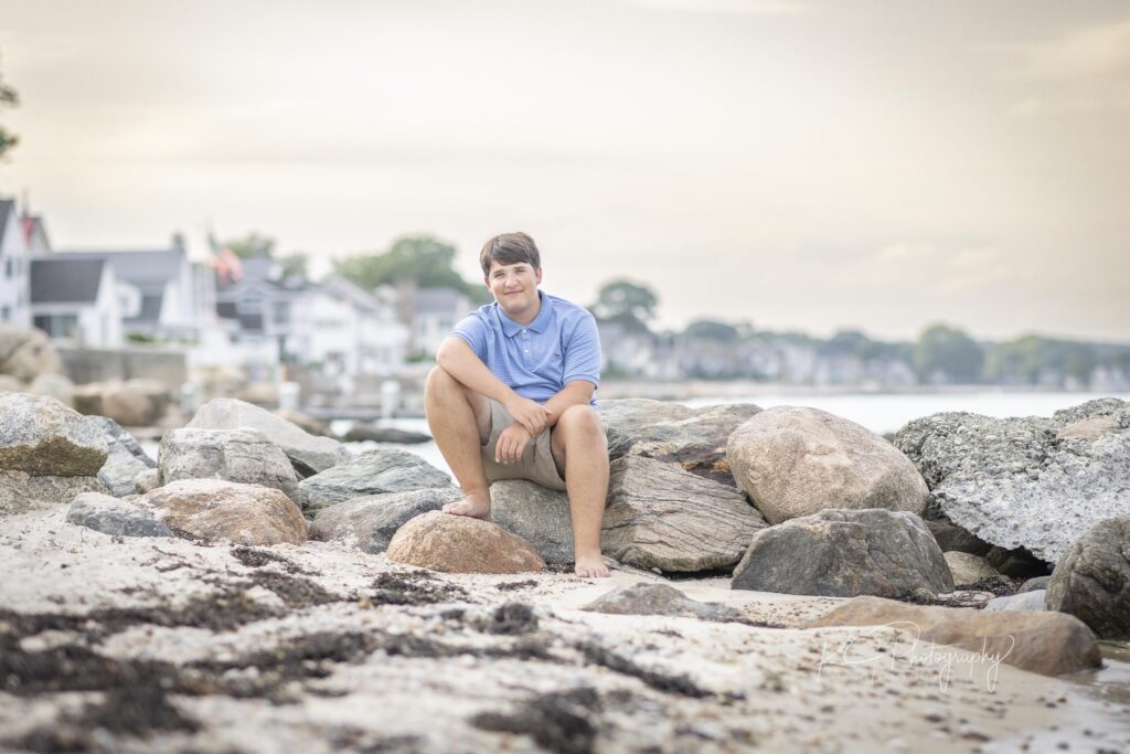 Rob Faber Photography | FBR Media | Senior Guys Portraits | Male senior sitting on coastal rocks during a relaxed beach portrait session at sunset in Connecticut