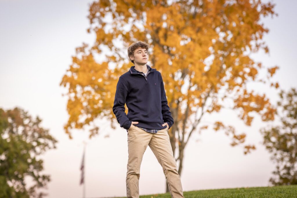Rob Faber Photography | FBR Media | Senior Guys Portraits | Male senior portrait outdoors beneath vibrant autumn leaves during a relaxed fall portrait session in Connecticut