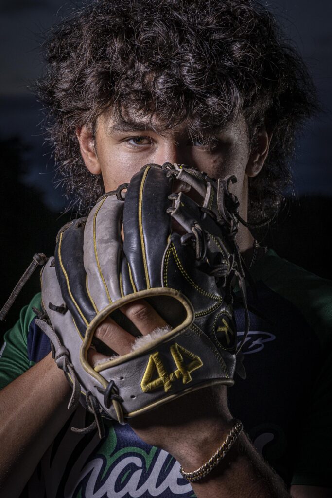 Rob Faber Photography | FBR Media | Senior Guys Portraits | Close-up dramatic baseball portrait featuring a senior athlete holding a glove over part of his face with intense cinematic lighting