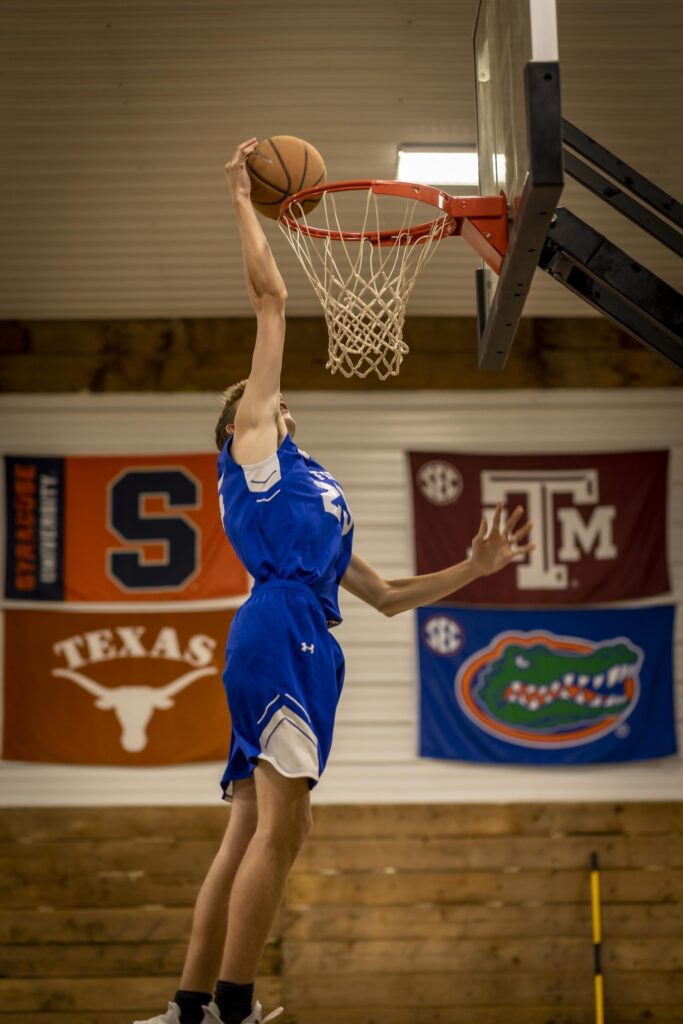 Rob Faber Photography | FBR Media | Senior Guys Portraits | High school basketball player performing a dunk in a gymnasium during a cinematic CT senior sports portrait session