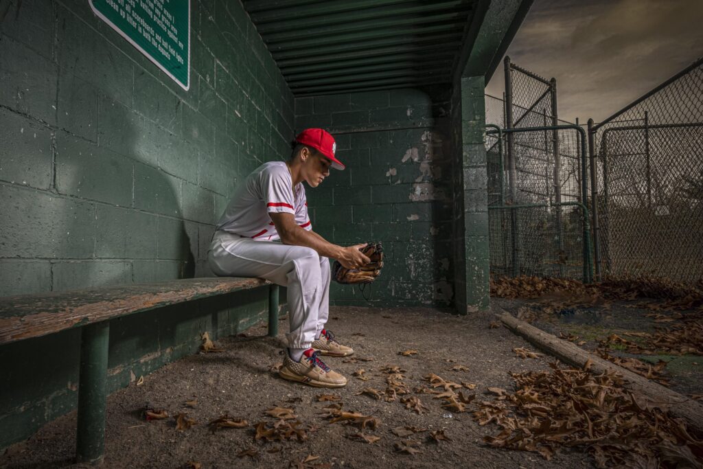 Rob Faber Photography | FBR Media | Senior Guys Portraits | Moody dugout baseball portrait featuring a Connecticut senior athlete in uniform during a cinematic sports photography session