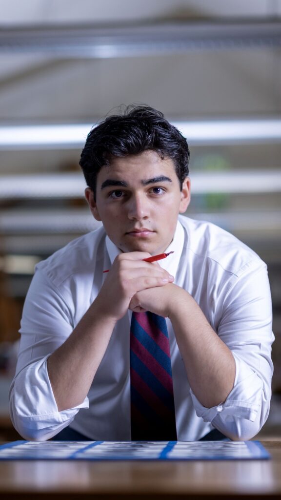 Rob Faber Photography | Headshot in CT | Senior Boy leaning on his elbows while holding his hands in front of his chin holding a pencil.