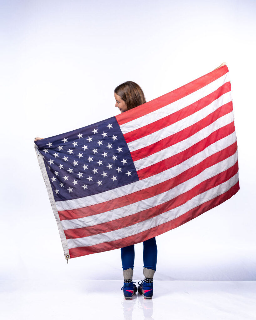 Rob Faber Photography | CT Photographer | SHS girls soccer player holding a large American flag spread wide behind her against a clean white studio backdrop during media day.